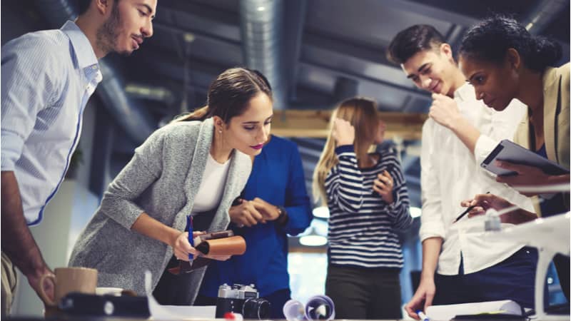 a group of coworkers around a table working on a project