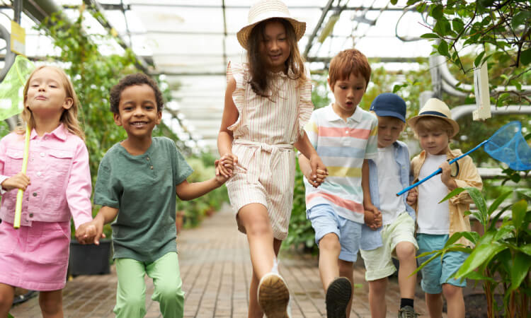 children holding hands and walking in a garden